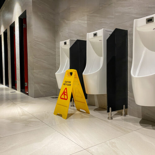 Washroom Cleaning & Sanitation Solutions - Urinals with wet floor sign